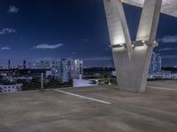 a concrete area with large white and blue buildings in the background at night and a city sky