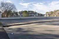 a empty street and an intersection with cars on the road near it in front of a home