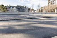 a empty street and an intersection with cars on the road near it in front of a home