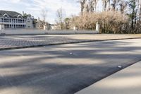 a empty street and an intersection with cars on the road near it in front of a home