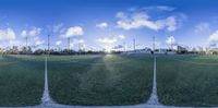 the four - panoramic image shows a field of grass and a soccer field with goal posts on each side, with buildings in the background