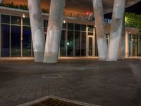 a night time image of some empty walkway next to an entrance to a building with glass windows