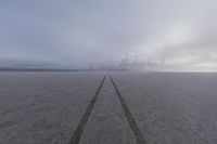 a city is visible in a foggy photograph on the beach, in front of some footprints