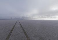 a city is visible in a foggy photograph on the beach, in front of some footprints