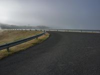 a roadway is being constructed on a foggy day by the water's edge