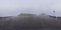 a road with several flags on top of it with fog in the air and a mountain in the background