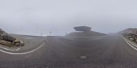 a long curved road in a foggy area with signs on it and a stone wall