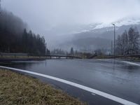 wet roadway with highway signs, snowy mountain range in background, in motion of raining