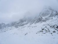 skier standing on top of snow covered mountain in the wilderness under cloudy skies and clouds