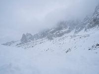 skier standing on top of snow covered mountain in the wilderness under cloudy skies and clouds