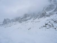 skier standing on top of snow covered mountain in the wilderness under cloudy skies and clouds