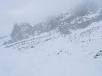 skier standing on top of snow covered mountain in the wilderness under cloudy skies and clouds