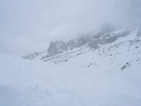 skier standing on top of snow covered mountain in the wilderness under cloudy skies and clouds