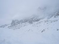 skier standing on top of snow covered mountain in the wilderness under cloudy skies and clouds