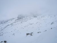 skier standing on top of snow covered mountain in the wilderness under cloudy skies and clouds