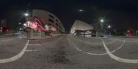 a very wide picture of an intersection with a big building behind it on a foggy night