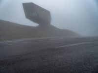 a very large building in the middle of the foggy hillside of a road