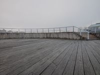 wooden boardwalk on the seafront at the foggy day in a city area with an observation point looking down over a lake