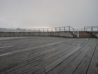 wooden boardwalk on the seafront at the foggy day in a city area with an observation point looking down over a lake