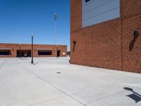 a small kid riding his skateboard outside of a building with red bricks in the background