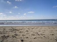 footprints are seen on the sand at the beach as the waves move in nearby, near by