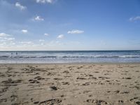 footprints are seen on the sand at the beach as the waves move in nearby, near by