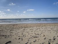 footprints are seen on the sand at the beach as the waves move in nearby, near by