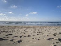 footprints are seen on the sand at the beach as the waves move in nearby, near by