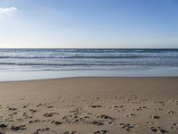 footprints on the sandy beach as the sun shines brightly above the sea foams