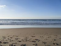 footprints on the sandy beach as the sun shines brightly above the sea foams