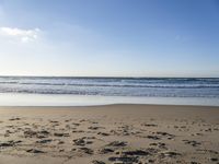 footprints on the sandy beach as the sun shines brightly above the sea foams