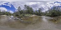 a wide picture looking down a river surrounded by trees and rocks, the image is 360 - angle view