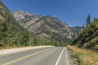 a highway going down into a big wooded landscape in the mountains under a clear sky