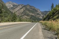 a highway going down into a big wooded landscape in the mountains under a clear sky