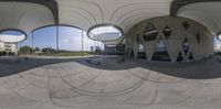 large circular building with benches near by and another building on the other side of it