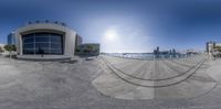 an upside down fish eye lens view of buildings in the distance with a man riding a skateboard