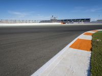 the green road and orange and white stripe line at an event near the racetrack and stadium