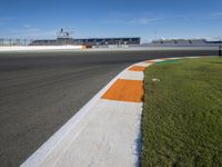 the green road and orange and white stripe line at an event near the racetrack and stadium