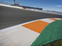 the green road and orange and white stripe line at an event near the racetrack and stadium