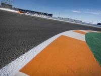 the green road and orange and white stripe line at an event near the racetrack and stadium