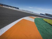 the green road and orange and white stripe line at an event near the racetrack and stadium