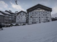 a skier is going up a hill outside a big building with glass windows and a few ski poles