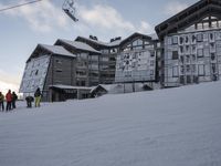 a skier is going up a hill outside a big building with glass windows and a few ski poles