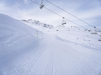 snow covered slope in the middle of a ski area as people ski on it near ski lift