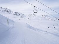 snow covered slope in the middle of a ski area as people ski on it near ski lift