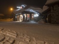 a lit up store is shown in the snow with people coming into it at night