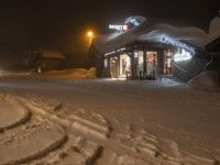 a lit up store is shown in the snow with people coming into it at night