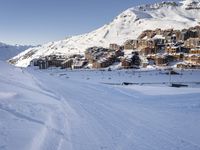 an empty snowy mountain area with buildings on it and skiiers in the foreground