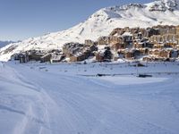 an empty snowy mountain area with buildings on it and skiiers in the foreground