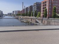 there is a man in white jacket walking along a bridge near water and buildings with boats